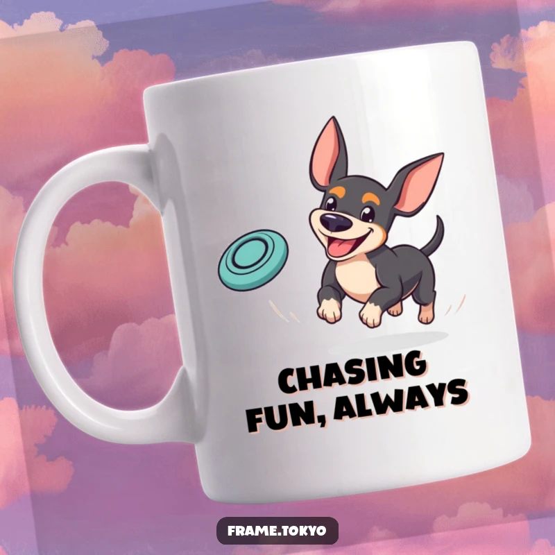 Funny pinscher mug showing a dog with a goofy grin playfully chasing a bouncing mini frisbee, capturing pure playtime joy.