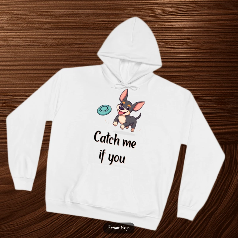 Funny pinscher hoodie featuring a dog with a goofy grin playfully chasing a bouncing mini frisbee, radiating pure playful spirit.