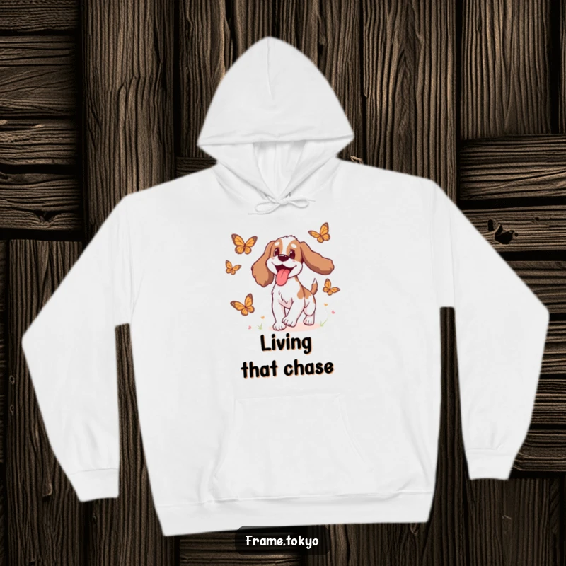 Funny Spaniel Hoodie showing a spaniel with its tongue out in delight pursuing animated butterflies through a whimsical landscape.